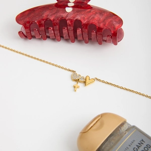 Detail of gold heart and cross pendants on thin chain necklace with pave zircon stones