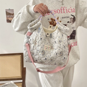 Détail d'un sac matelassé à rayures bleues avec oursons et bandoulière rose ajustable