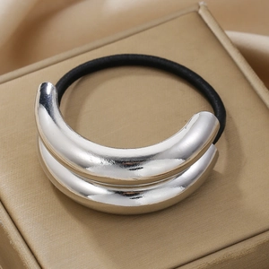 Close-up of shiny silver metal hair cuff with black elastic tie on a luxury jewelry box