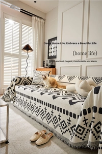 Detail of bohemian chenille sofa cover with black and white geometric pattern and tassels