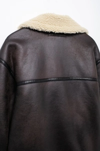 Detail shot of the back of a brown faux leather shearling jacket with cream wool collar