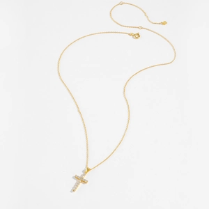 Macro detail of the golden S925 sterling silver cross pendant with pavé set white zircon