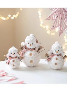 Detailed view of three plush pink snowmen with soft fleece texture and wood buttons