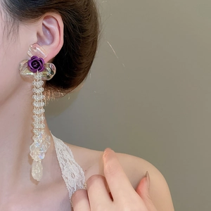 Detail view of long tassel earrings featuring purple rose decor and clear beaded chains