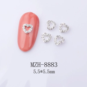 Macro shot of 5.5mm silver heart nail charms with micro crystals on coral manicure