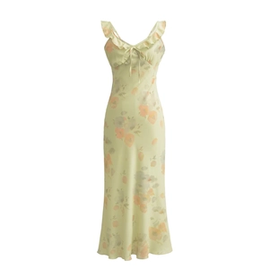 Robe longue fleurie vert clair avec volants et détail noué sur fond blanc épuré