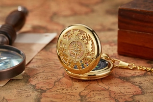 Macro detail of a golden vintage compass pocket watch on an old antique map with magnifier