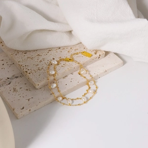 Double-layered gold chain bracelet featuring natural white pearls and a lobster clasp