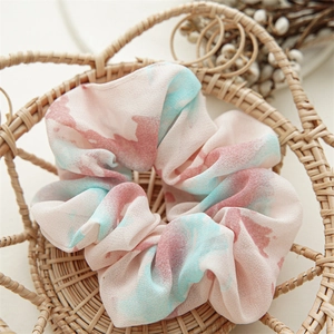 Macro shot of large floral tie-dye chiffon scrunchie in a woven wicker basket