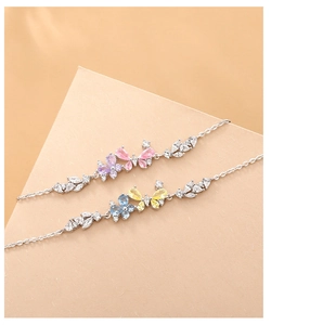 Detail of silver butterfly bracelets with pink and blue zircons on a geometric background