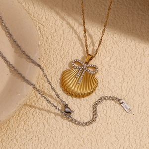 Detailed macro view of 18K gold plated scallop pendant with rhinestone bow and steel tag