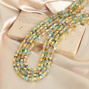 Collier en pierres naturelles colorées avec perles carrées dorées sur socle en pierre
