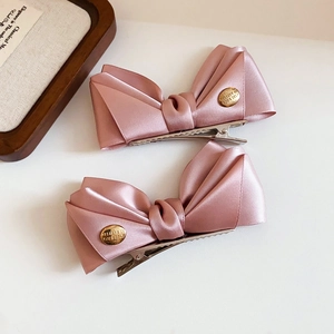 Detail of pink satin bow hair clips with engraved gold decorative metal buckles