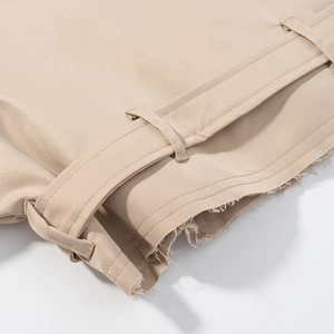 Detailed macro view of khaki cotton shorts featuring frayed hem and wide belt loops