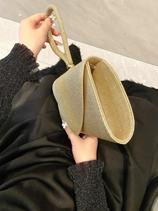 Elegant gold sequined clutch handbag for evening galas held by a model in a natural setting