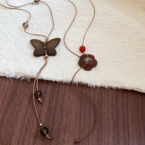 Détail de pendentifs rétro en bois de papillon et de fleur sur colliers en corde de cire