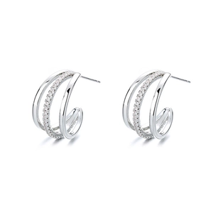Macro detail of silver C-shaped earrings with triple-layered bands and pavé cubic zirconia
