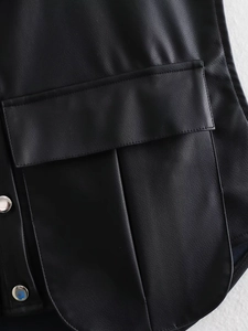 Detail of black faux leather vest showing pocket flap and silver metallic button snap
