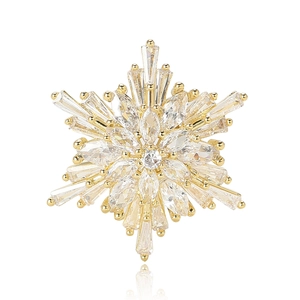 Elegant gold snowflake brooch with sparkling cubic zirconia crystals on white background