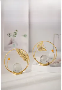 Detail of gold metal ring stands with hollow leaf and butterfly decor and crystal sphere