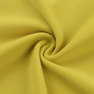 Macro detail of mustard yellow dress fabric showing fine grainy texture and drape