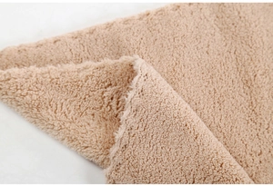 Macro view of plush beige faux fur fabric with dense curly texture and thick soft pile