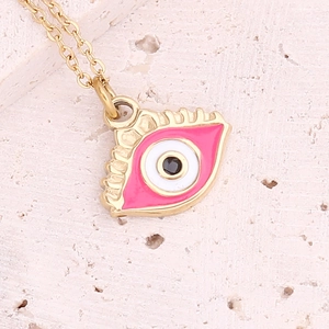 Golden necklace with a pink enamel evil eye pendant on a textured stone background