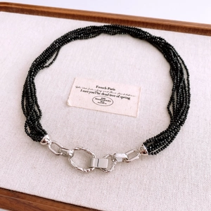 Détail d'un collier à plusieurs rangs de perles noires et fermoir argenté texturé