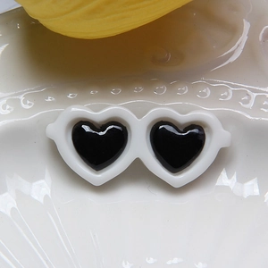 Close-up of white heart-shaped sunglasses accessory on a white ceramic plate