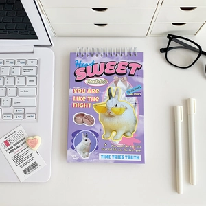 Purple spiral notebook with retro rabbit collage design in a tidy workspace setting