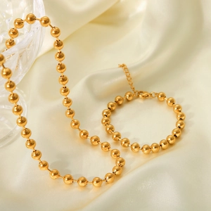 Detailed view of 18K gold-plated stainless steel ball chain jewelry on silk fabric