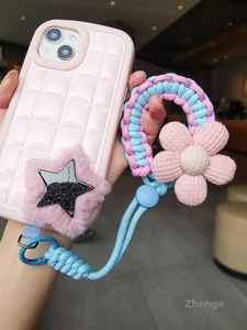 Detailed view of pink quilted phone case with braided strap and plush star charm
