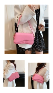 Detail view of the pink faux leather shoulder bag with gold hardware and saddle silhouette