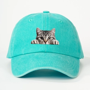 Detailed view of funny peeking cat graphic on turquoise washed cotton baseball cap