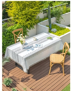 Detail of bohemian rectangle tablecloth featuring black geometric patterns and white tassels