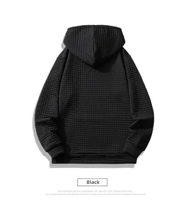 Close-up of black men's hoodie featuring textured waffle fabric and ribbed cuffs detail