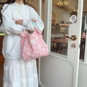 Detail of pink floral quilted handbag with soft cotton texture and light blue striped handles