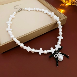 Detail of cross and pearl necklace with a black beaded bow pendant and shiny rhinestones
