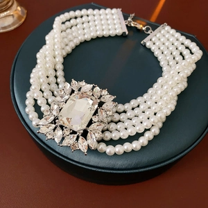 Close-up of multi-layer pearl necklace with a large rhinestone pendant on a green stand