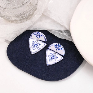 Close-up of geometric blue and white porcelain earrings on dark blue felt padding