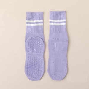 Detail of purple yoga socks featuring anti-slip grippers and white athletic stripes