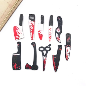 Flat lay of creative acrylic Halloween knife pendants including bloody axes and saws