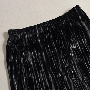 Vue détaillée de la texture du tissu plissé noir métallisé et de la taille élastique