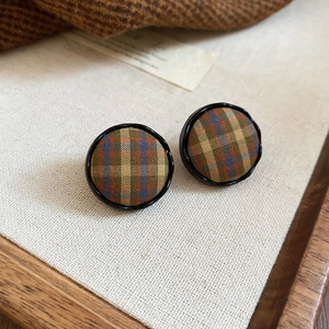 Macro shot of British style checkered fabric stud earrings with elegant black borders
