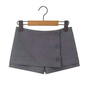 Dettaglio della gonna-pantalone grigio scuro con tre bottoni e orlo asimmetrico