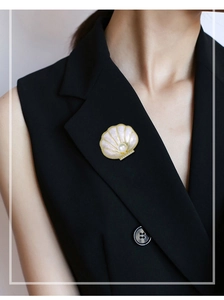 Detail of elegant shell brooch with pink pearl luster on black suit lapel