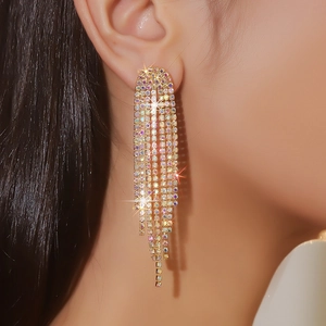 Close-up of long tassel earrings with sparkling AB rhinestones and gold-plated finish
