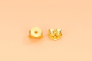 Close-up of golden S925 sterling silver butterfly earring backs with hallmark stamp