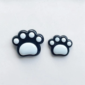 Macro view of black and white resin cat paw charms for DIY phone cases and hair clips