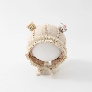 Detailed close-up of baby knit bonnet featuring lace edges and cute smile patches
